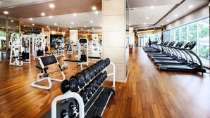 Un gimnasio moderno con máquinas de cardio, equipo de levantamiento de pesas y piso de madera.