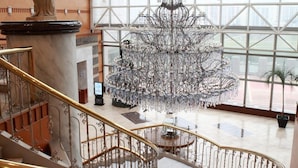 Un amplio atrio con una escalera de mármol, un gran candelabro y una estatua.