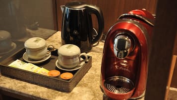 A coffee station with a black and red coffee maker, two cups, and a tray with coffee pods.