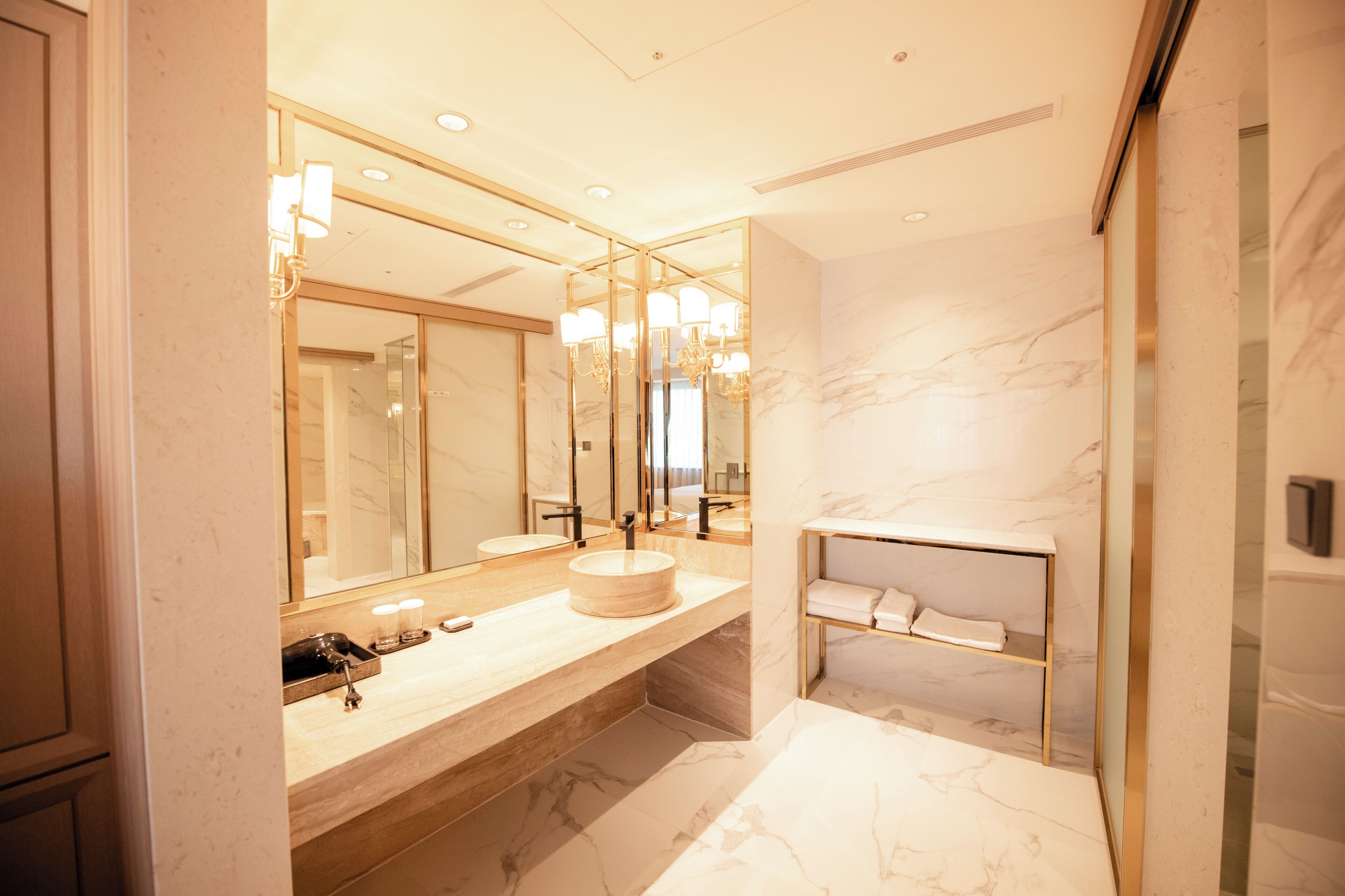 A modern bathroom with a large mirror, a round sink, and a built-in shelf.