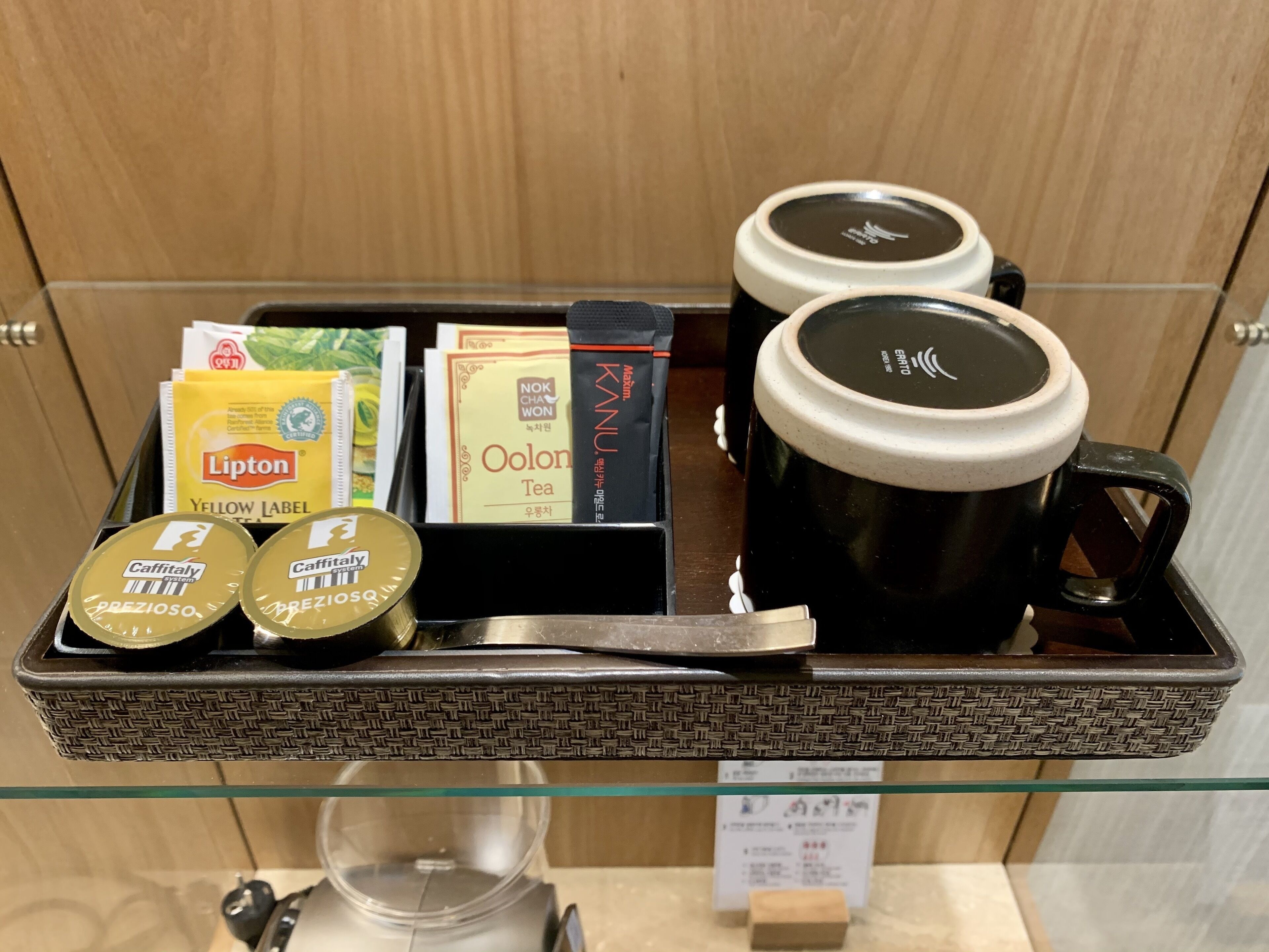 Una bandeja con tazas de café, bolsitas de té y cápsulas de café.
