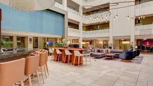 A spacious lobby with a central bar area, multiple seating options, and a high ceiling with hanging lights. - Crowne Plaza Charleston Airport - Conv Ctr by IHG (North Charleston)