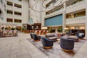 A spacious lobby with a high ceiling, multiple seating areas, a bar, and a large map on the wall.