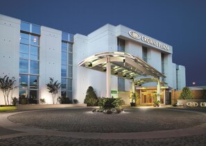 A modern hotel with a covered entrance, large windows, and a well-lit facade. - Crowne Plaza Charleston Airport - Conv Ctr by IHG (North Charleston)