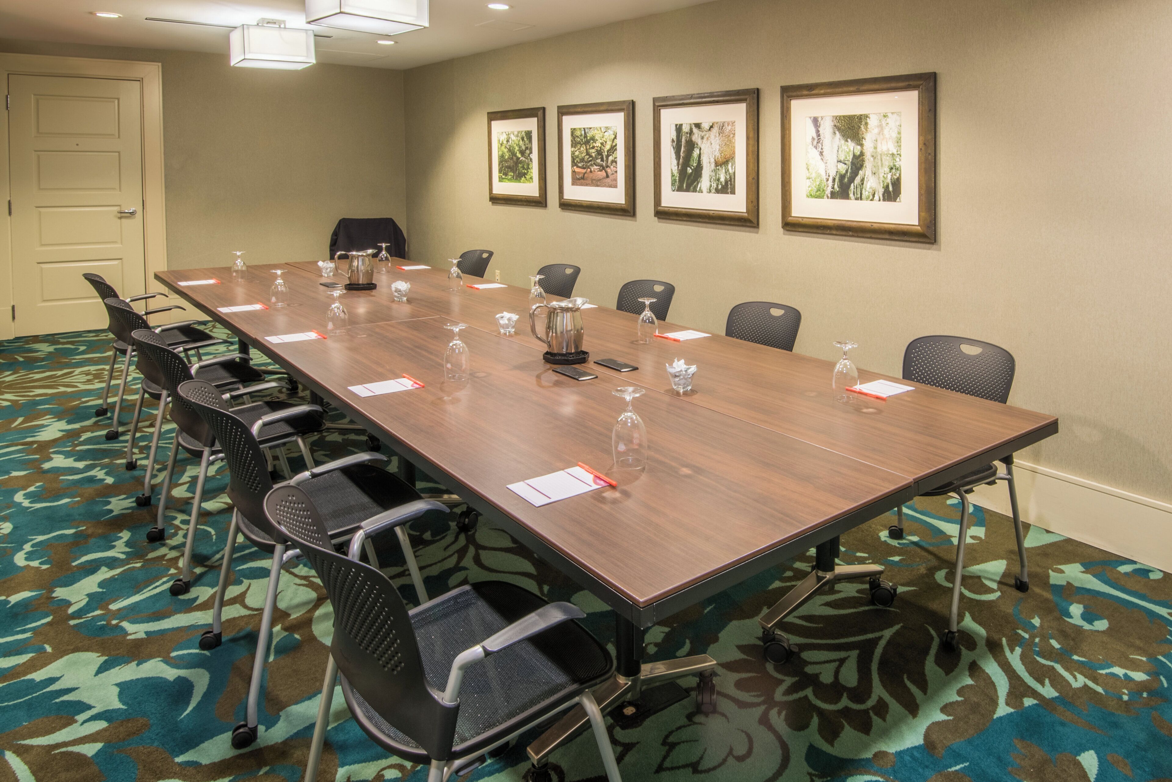 A conference room with a long table, chairs, and framed pictures on the wall.