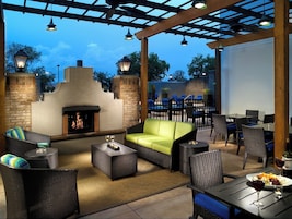 Un patio al aire libre con chimenea, mobiliario de mimbre y una zona de piscina.