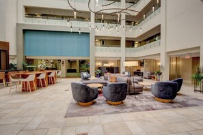 Un hall d’entrée spacieux avec un plafond haut, de nombreux espaces de détente et un bar central.