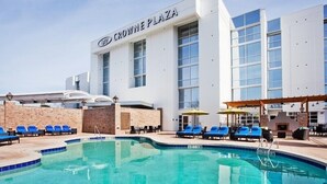 Un hotel con zona de piscina, sillas de descanso y cielo despejado.
