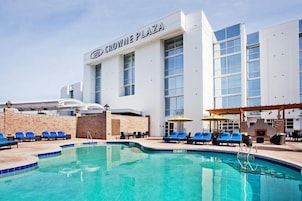 Un hotel con zona de piscina, sillas de descanso y cielo despejado.