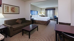 Una habitación de hotel con cama, sofá, mesa de centro y escritorio.