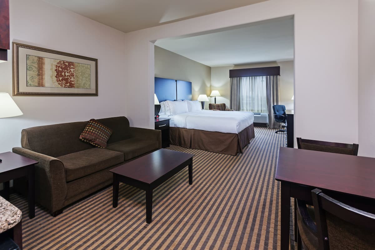 A hotel room with a bed, a sofa, a coffee table, and a desk.