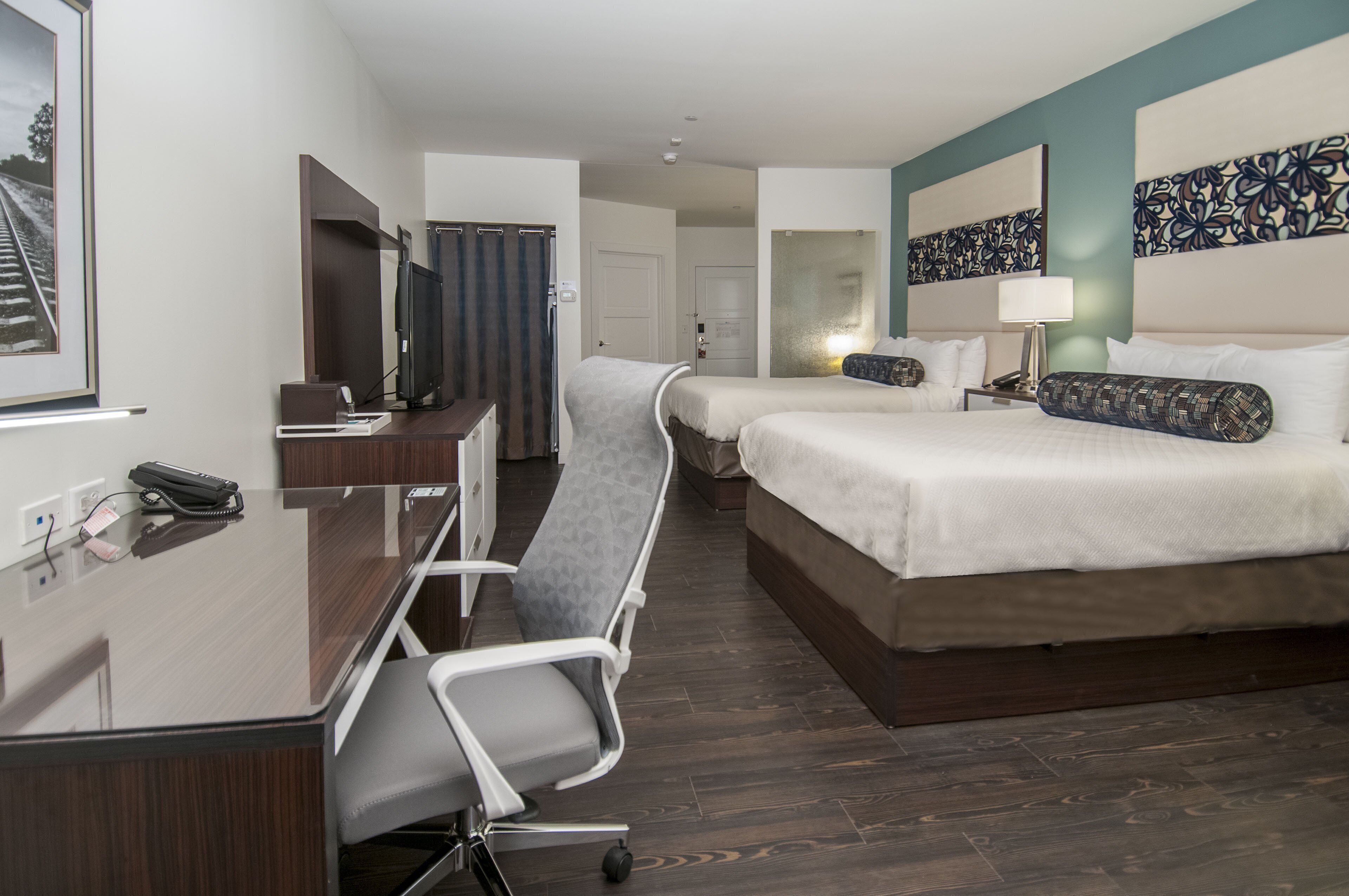 Habitación de hotel con escritorio, dos camas, una silla y televisión.