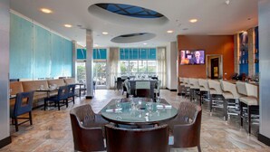 Eine moderne Hotelhalle mit Essbereich, Bar und Fernseher.