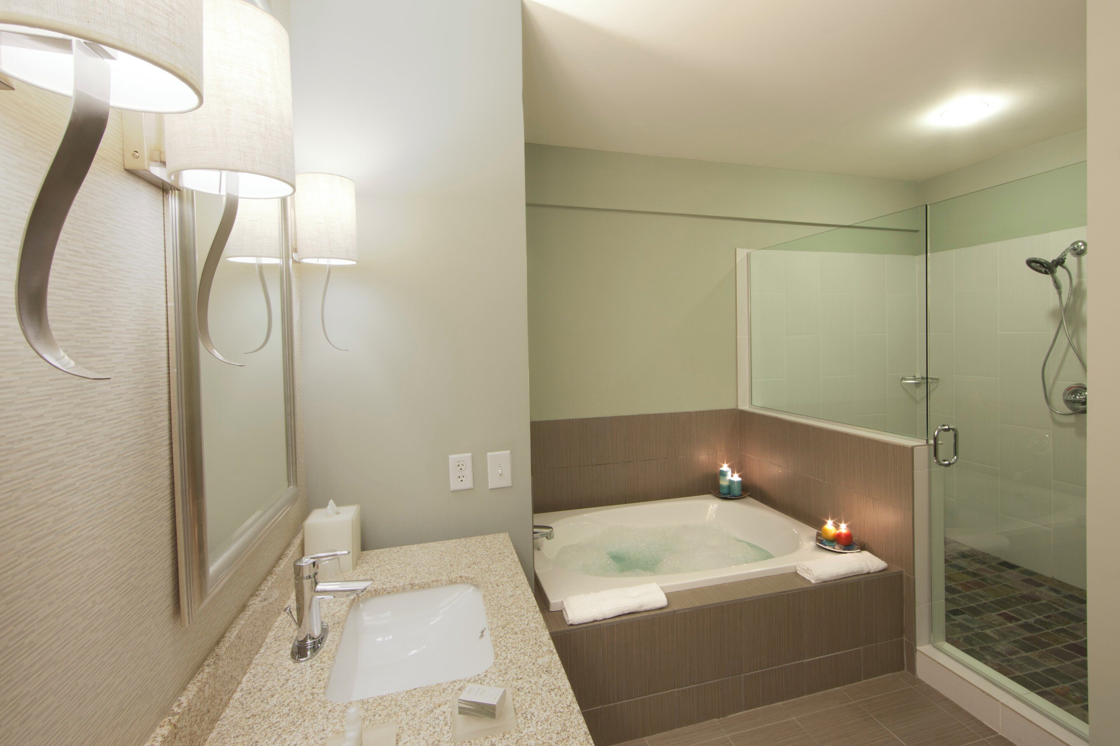 Une salle de bain moderne dotée d’une baignoire, d’une douche à parois de verre et d’un meuble-lavabo avec un évier et un miroir.