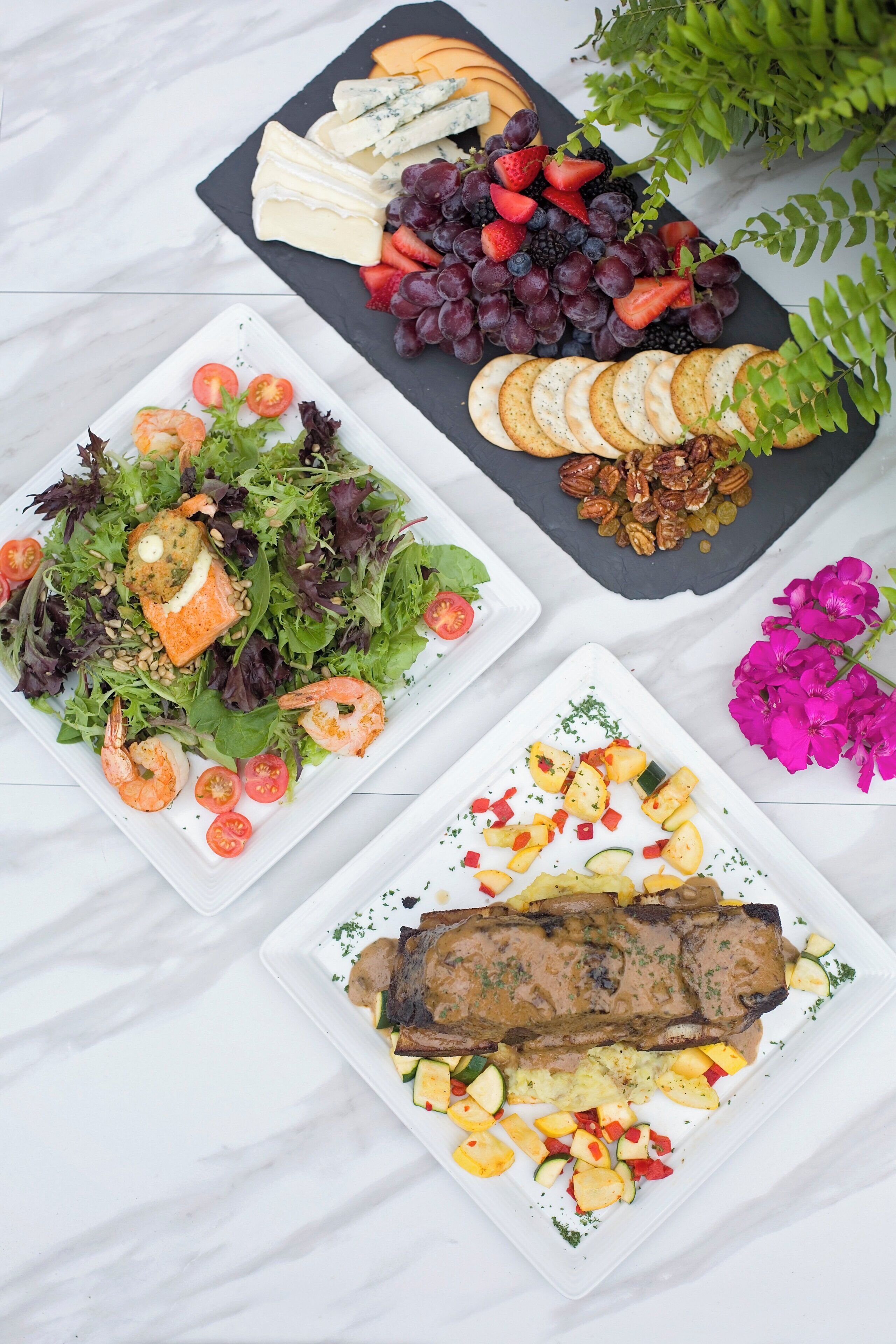 A variety of dishes including seafood, cheese, fruits, and vegetables, arranged on a marble surface.
