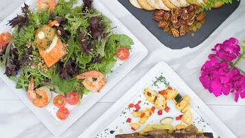 A variety of dishes including seafood, cheese, fruits, and vegetables, arranged on a marble surface.