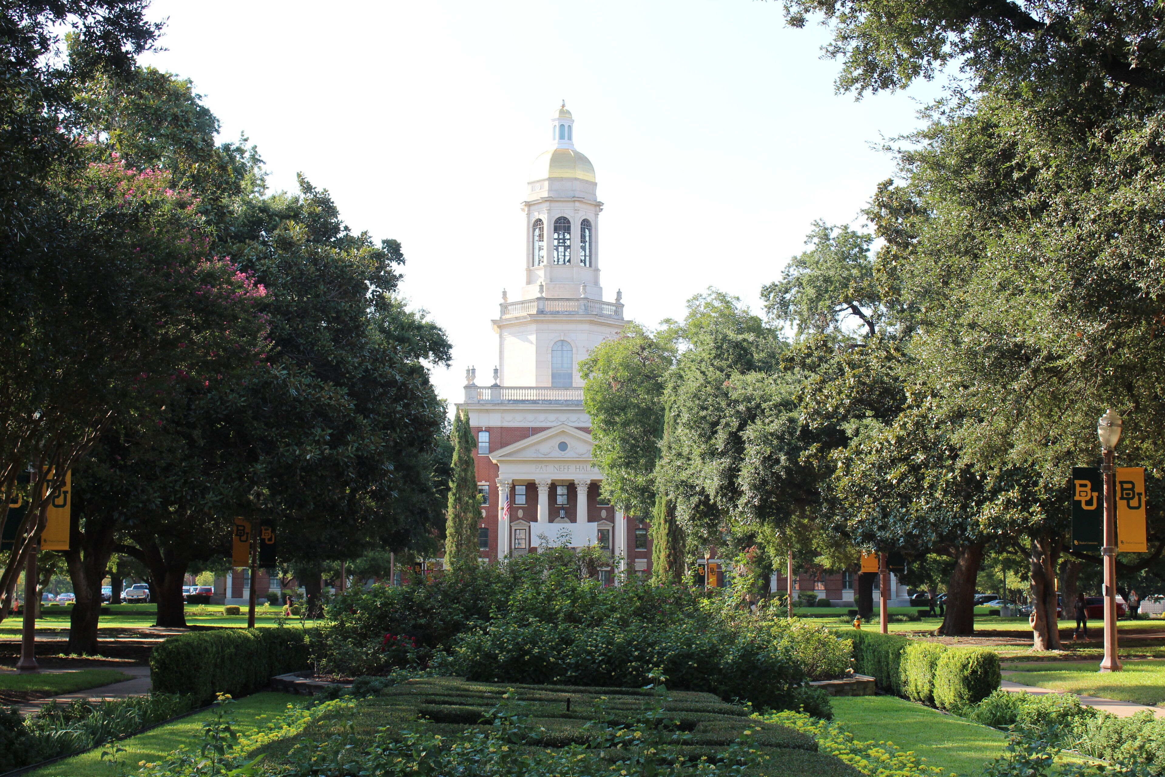 A building with a prominent tower and a well-maintained garden in front.