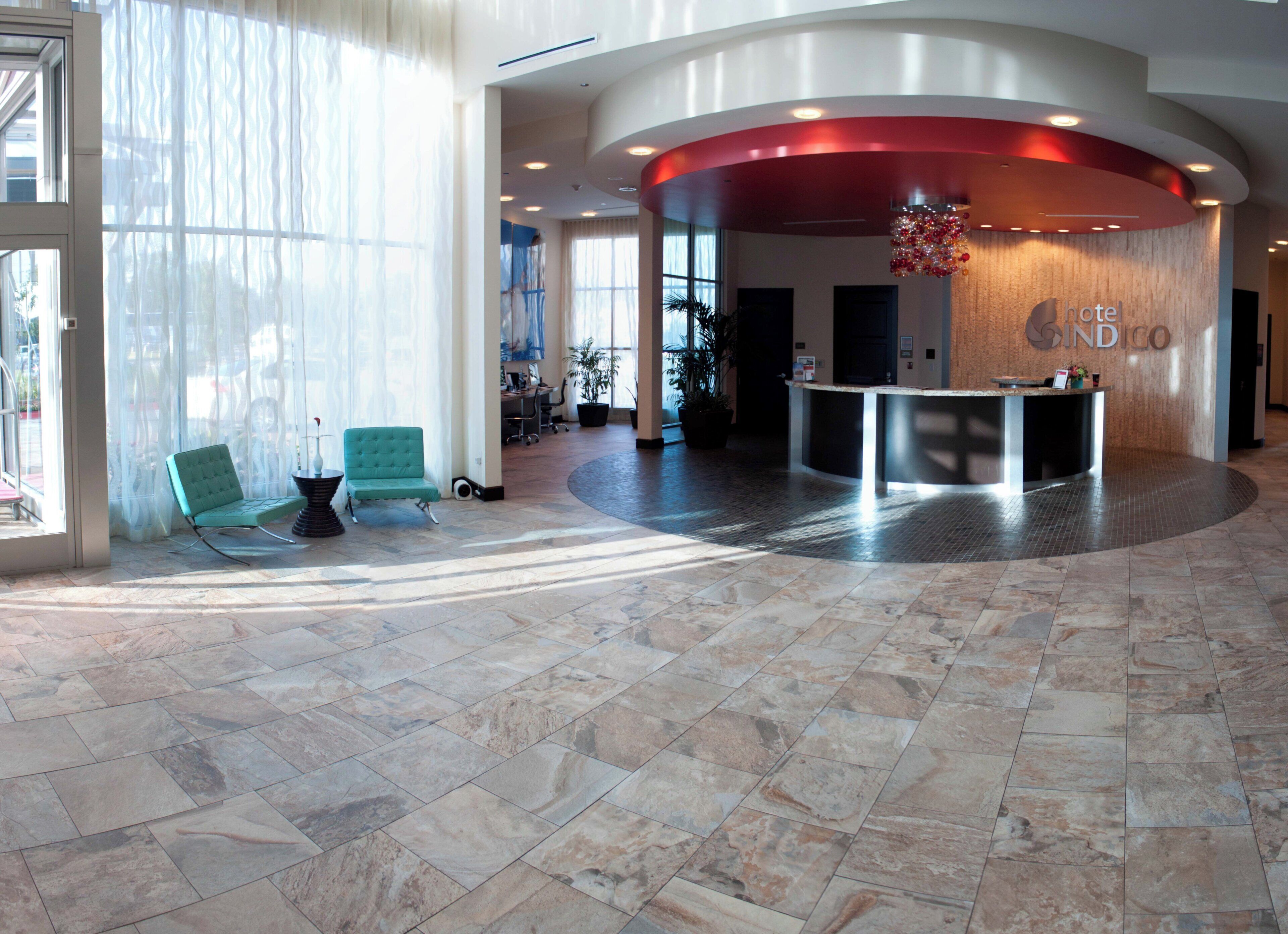 A hotel lobby with a reception desk, seating area, and large windows.