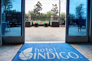 Entrada de un hotel con un felpudo azul que dice 'hotel INDIGO'.