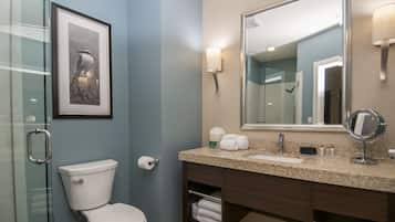 A bathroom with a toilet, sink, vanity, and a framed picture on the wall.