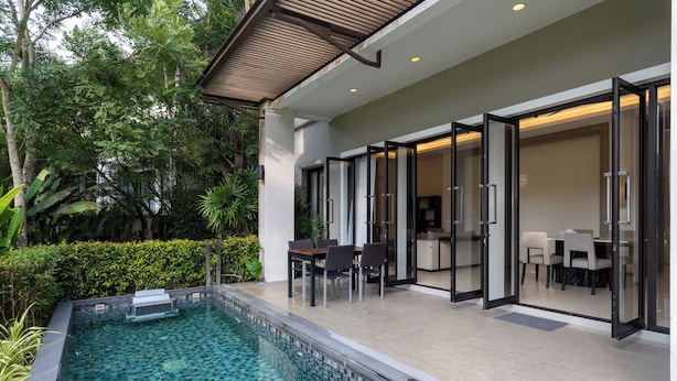 A modern outdoor pool area with glass doors leading to a dining area. - Tinidee Golf Resort Phuket (Kathu)