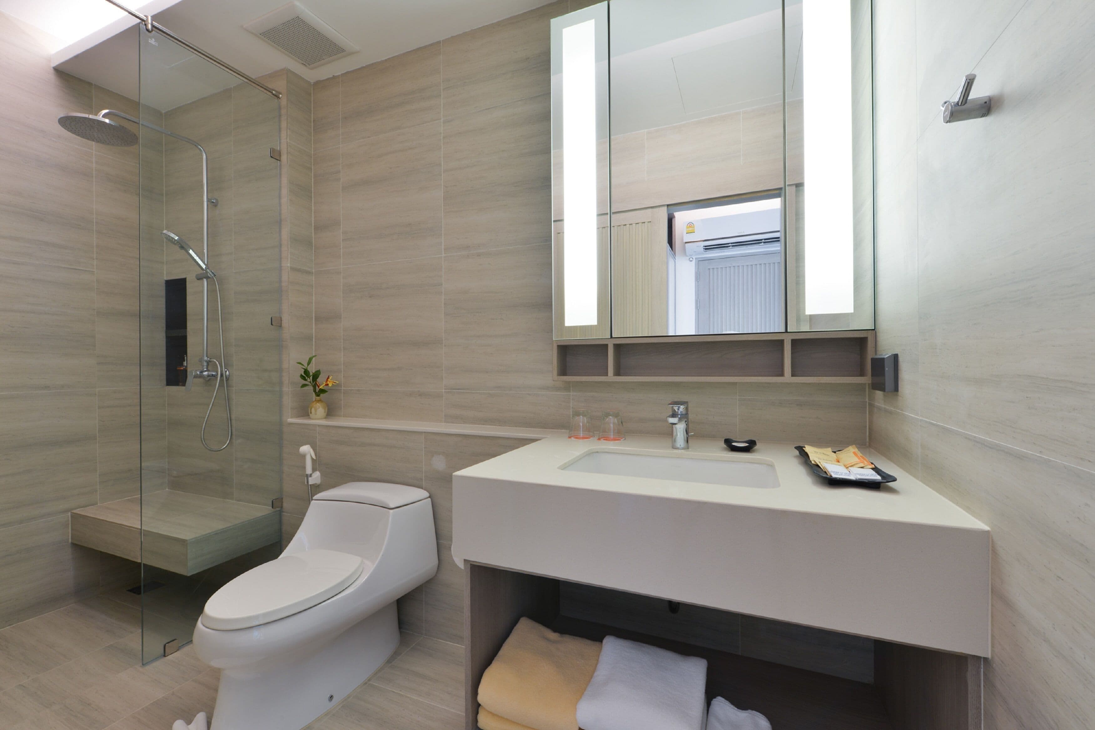 A modern bathroom with a glass-enclosed shower, a toilet, and a vanity with a mirror.