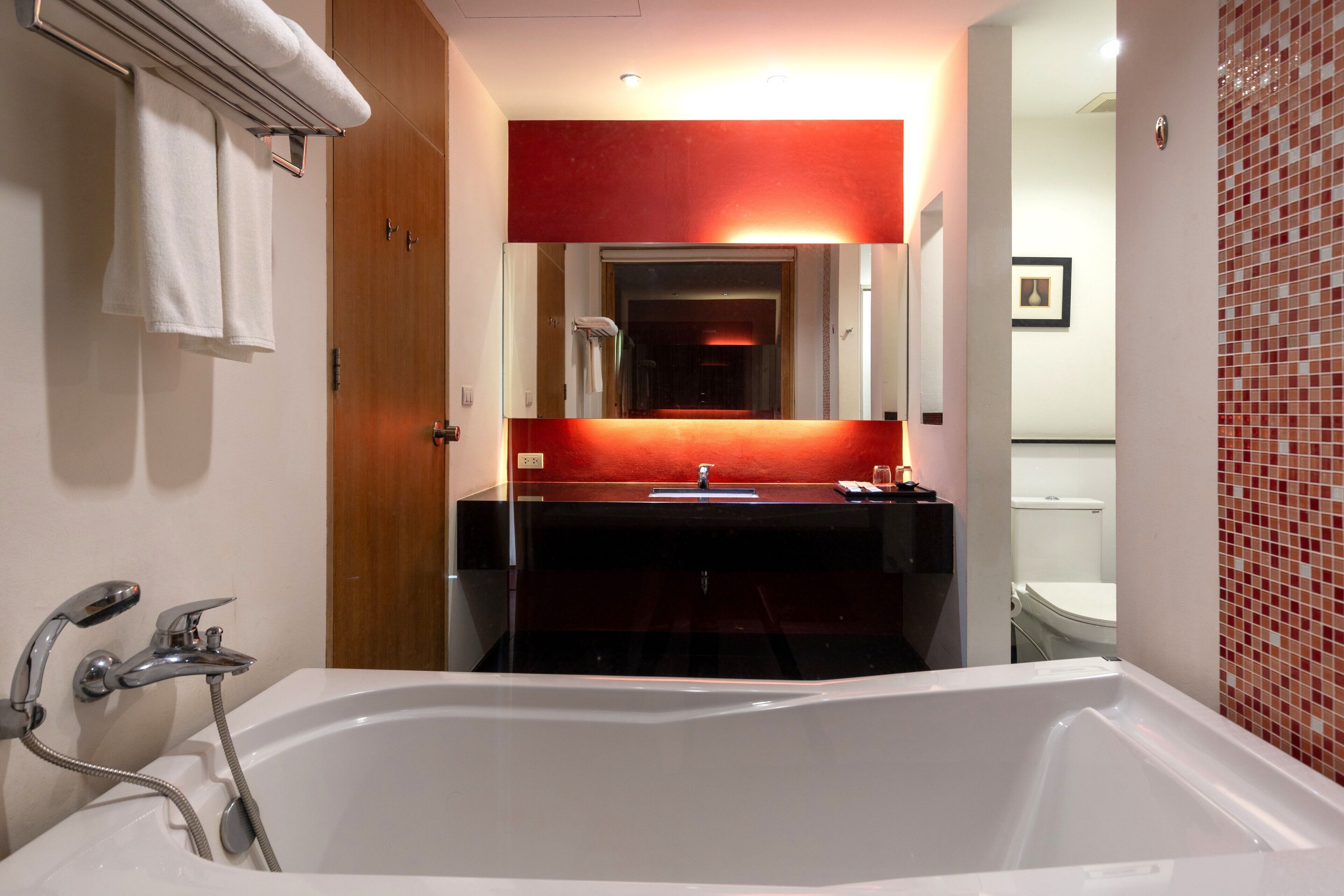 A bathroom with a bathtub, a mirror, a sink, and a toilet.