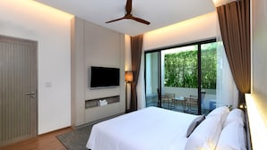 A modern hotel room with a large bed, a flat-screen TV mounted on the wall, a ceiling fan, and a view of the outdoors through a large window. - Tinidee Golf Resort Phuket (Kathu)
