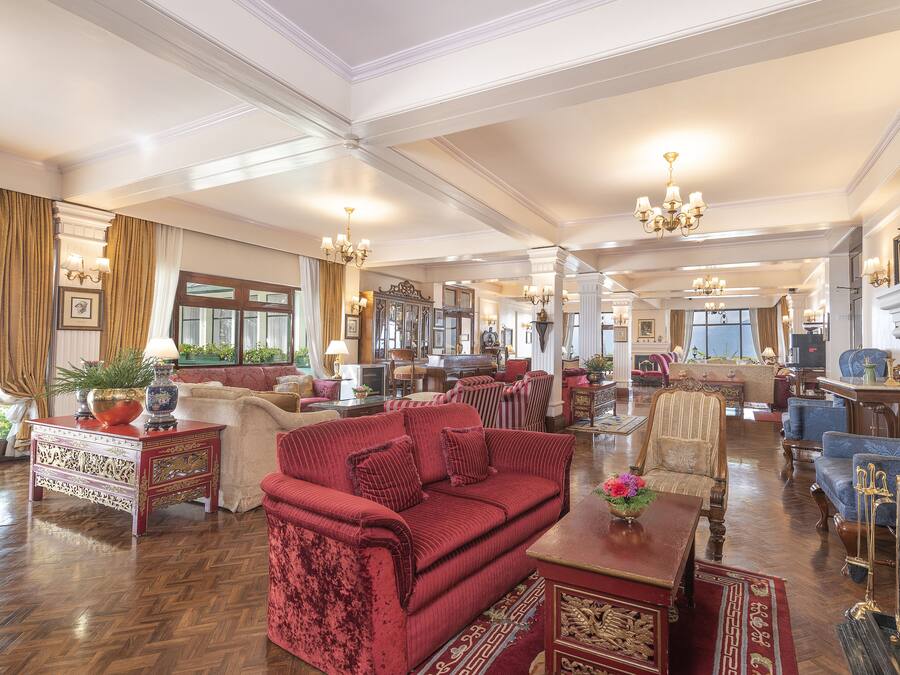A spacious, elegantly furnished living room with a red sofa, wooden furniture, and a fireplace.