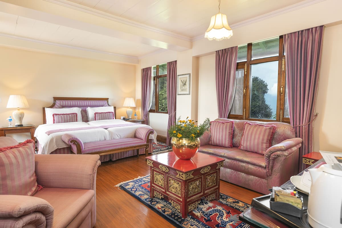 Quarto bem mobiliado com cama, sofá, mesa de centro e mesa de cabeceira.