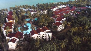 Un resort con varias edificaciones, una piscina central y vista al océano.