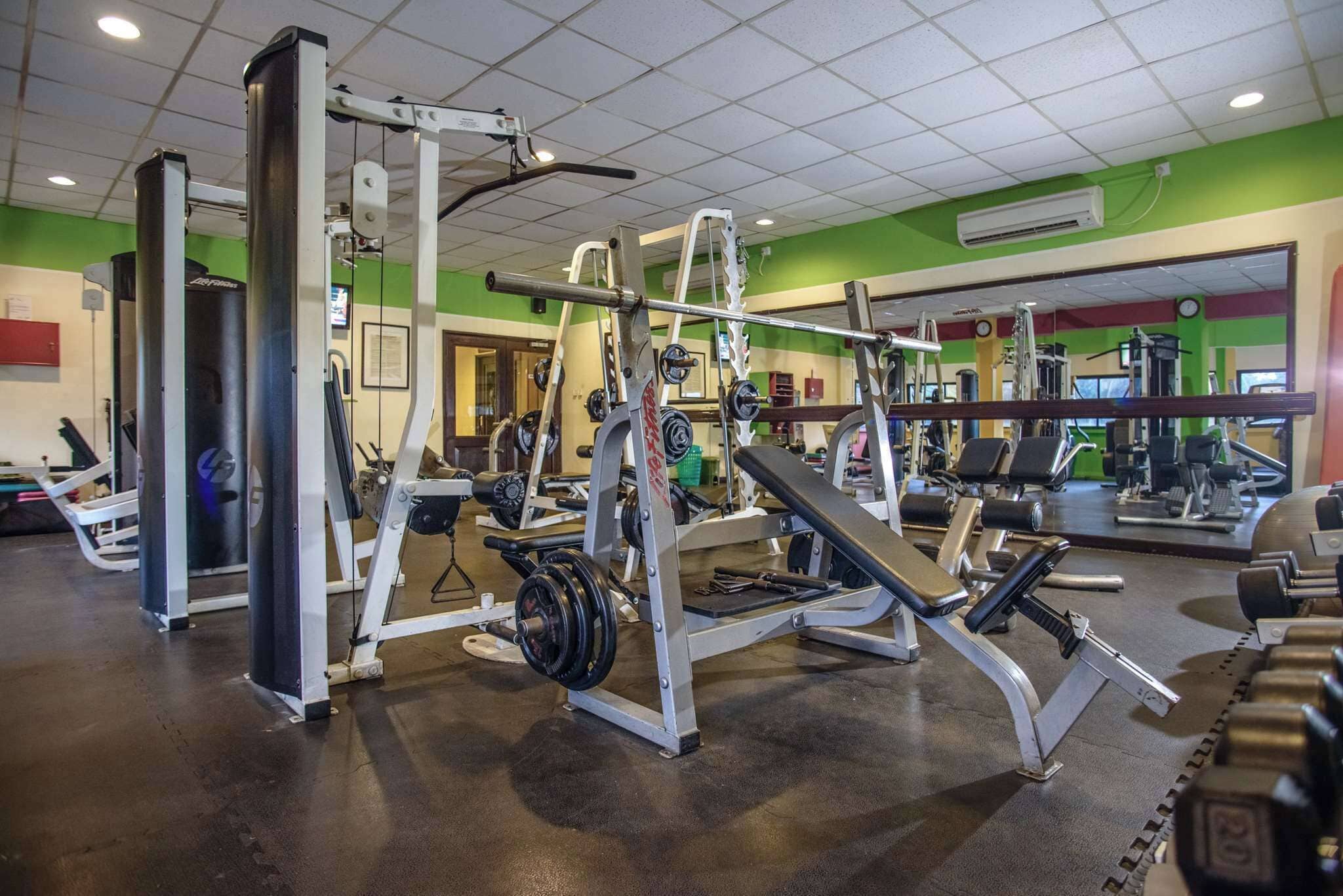 Ein Fitnessstudio mit unterschiedlichen Trainingsgeräten, darunter Kraftgeräte und Kurzhanteln.