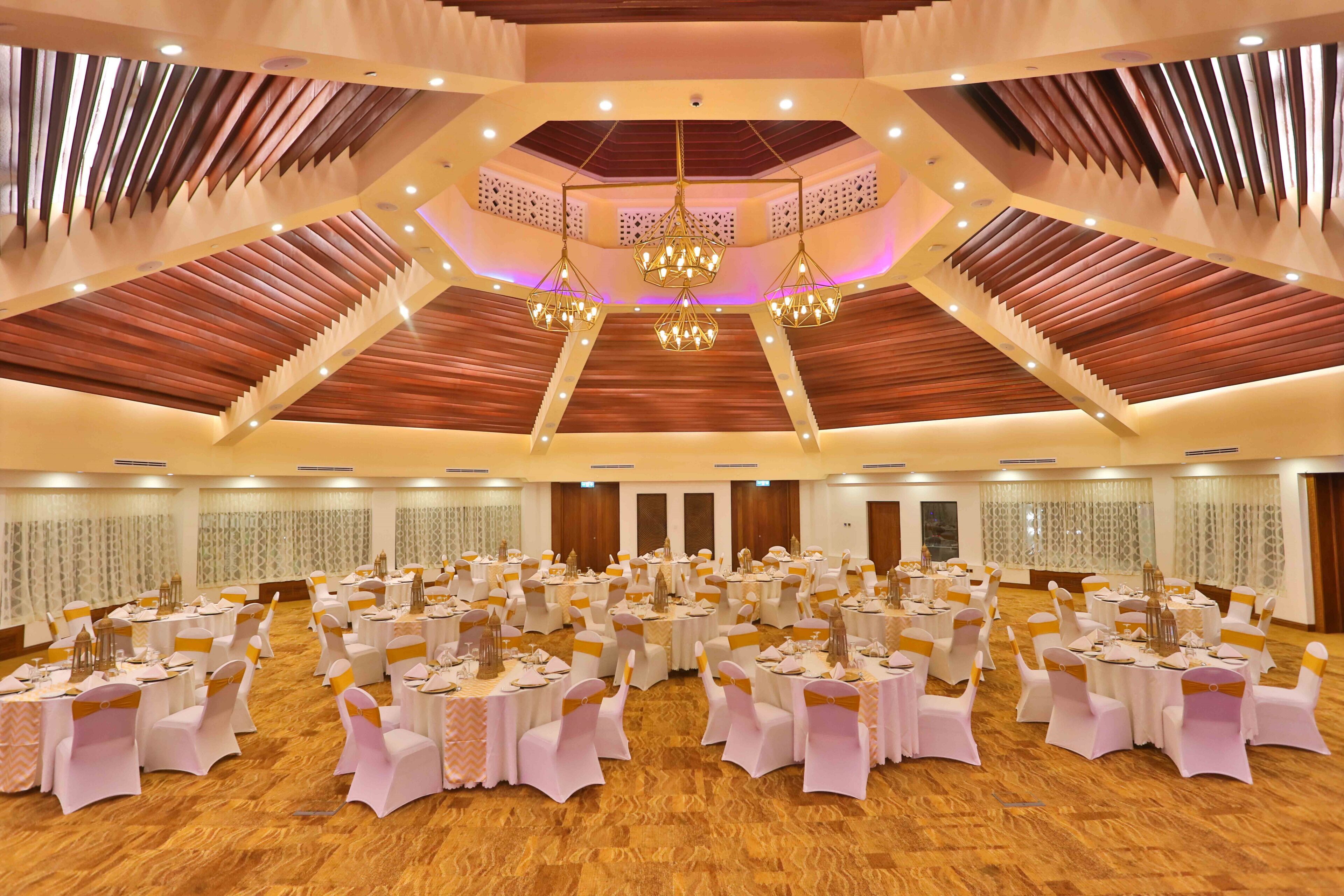 A banquet hall with tiered seating, chandeliers, and a wooden ceiling.
