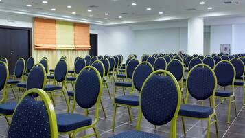 A conference room with rows of chairs, a stage, and a door.