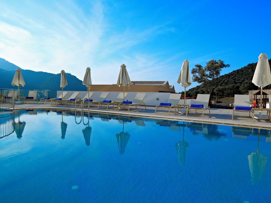 Una piscina techada, sombrillas, sillones reclinables de piscina