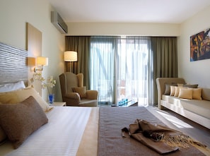 A hotel room with a large bed, two armchairs, a sofa, a desk, and a large window with curtains. - Filion Suites Resort & Spa (Mylopotamos)