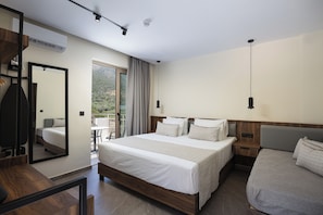 A hotel room with a bed, a desk, a chair, a mirror, and a view of the outdoors. - Filion Suites Resort & Spa (Mylopotamos)