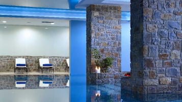 Zona de piscina con pilares de piedra, sillas de descanso y una piscina cristalina.