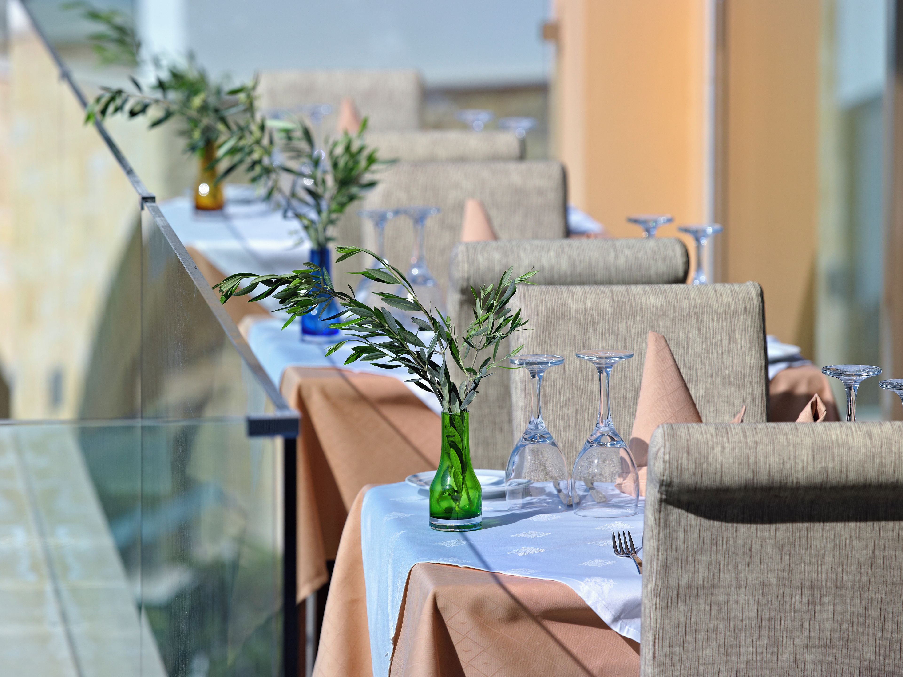 A dining table set with chairs, a vase with greenery, and wine glasses.