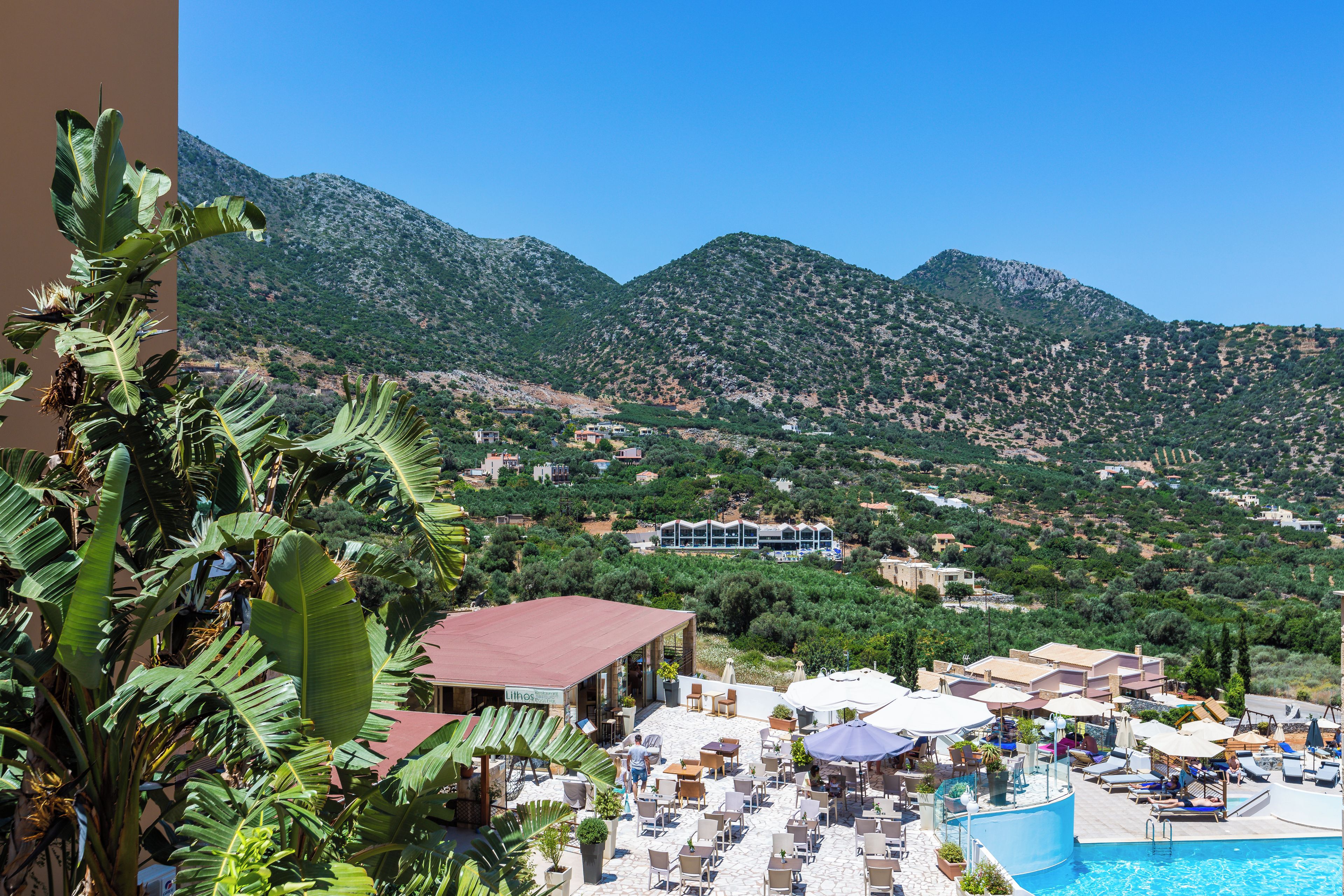 A resort with a pool, outdoor seating, and a view of the surrounding hills.