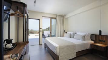 Habitación de hotel con cama, mesita de noche y escritorio con hervidor.
