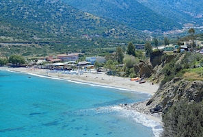 A coastal beach with clear blue waters, a sandy shore, and a backdrop of hills. - Filion Suites Resort & Spa (Mylopotamos)