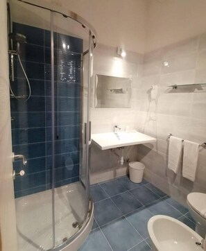 Bathroom features a glass-enclosed shower, sink, and toilet.