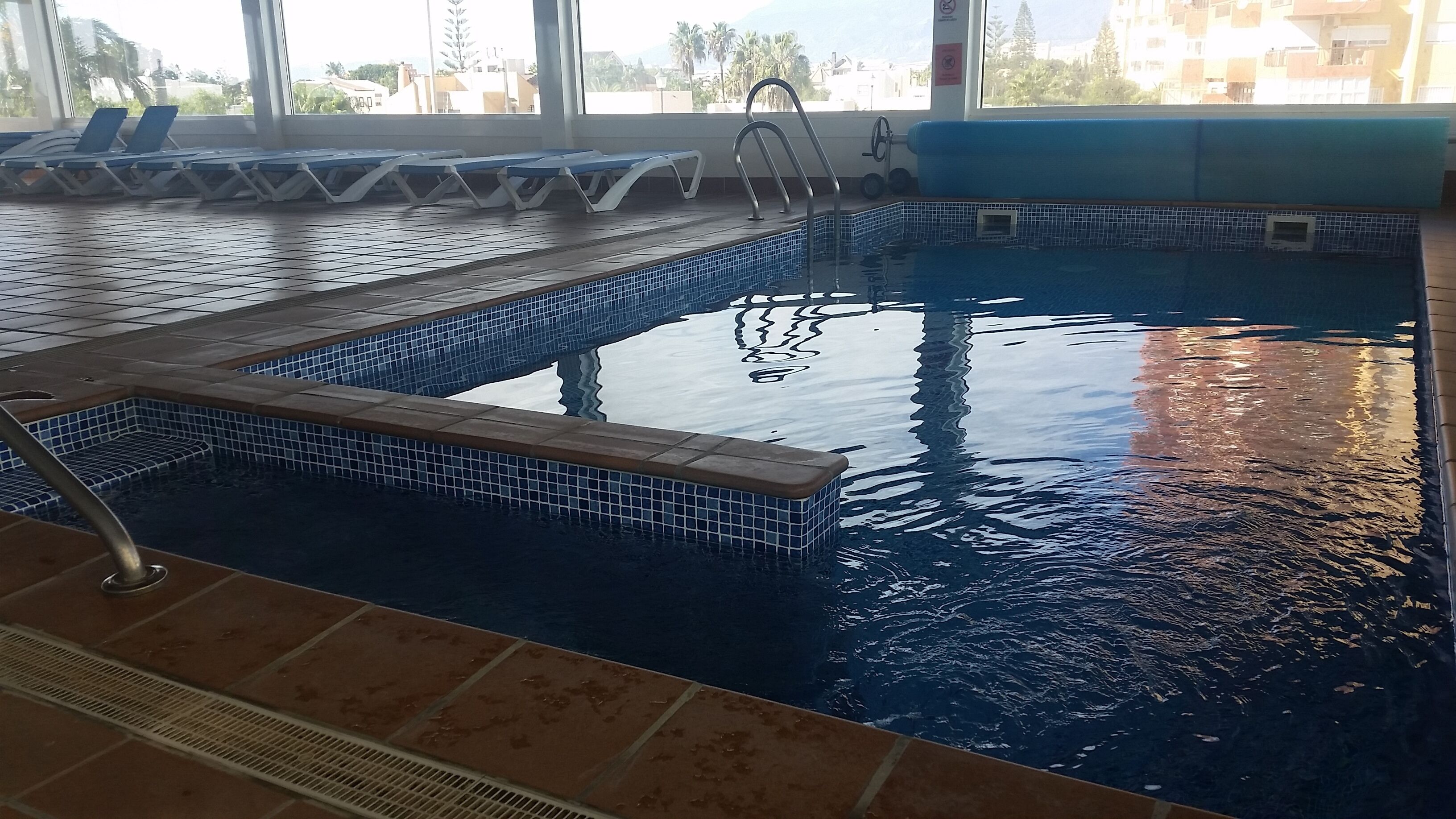 Una piscina interior amb parets de rajola i vista despejada a l'exterior.