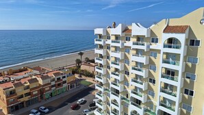 A multi-story hotel with balconies overlooking a beach.