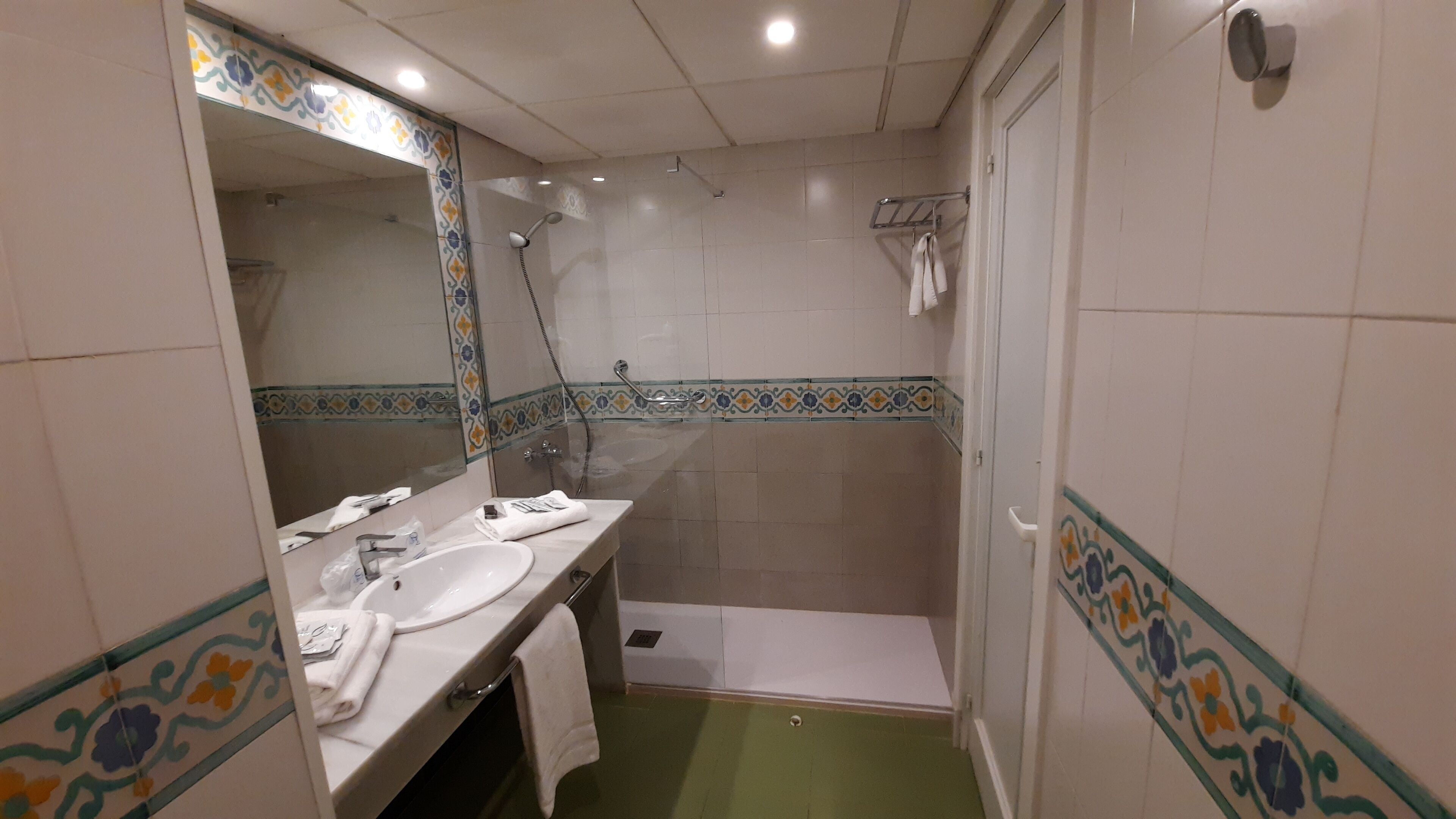 Une salle de bain équipée d’un lavabo, d’un miroir, d’une douche et de toilettes.
