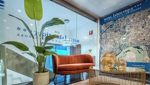 Un hall d’hôtel moderne, avec une grande carte, un canapé rouge moelleux et une plante en pot.