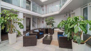 Un vaste espace intérieur aménagé avec des meubles en osier, des plantes en pot et un plafond en verre.
