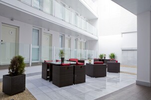 A modern outdoor seating area with wicker furniture and potted plants.