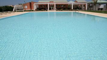 A large, clear swimming pool with a building in the background.
